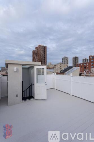 A balcony with a doorway leading to a building with a cloudy sky in the background.