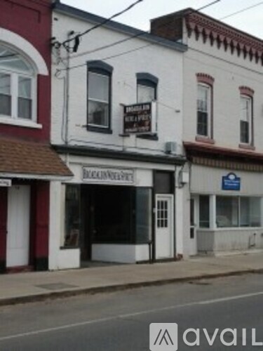 A white building with a red roof and a sign that says "Avail".