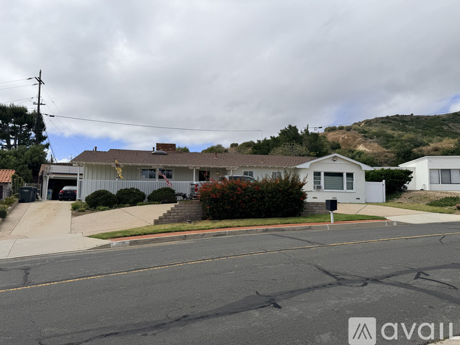 A street view of a residential area with houses and a hill in the background.