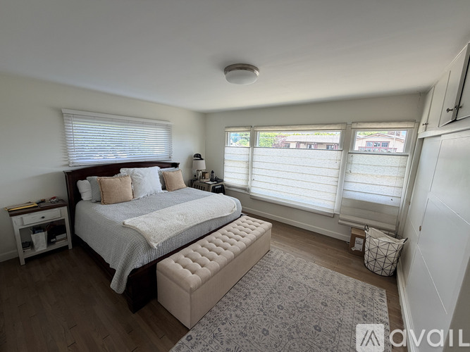 A bedroom with a large bed and a window with blinds.