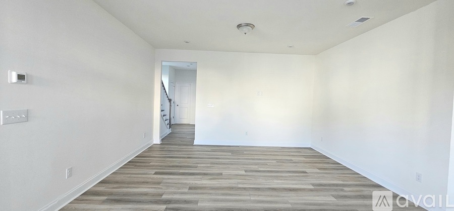 A spacious room with wooden flooring and white walls.