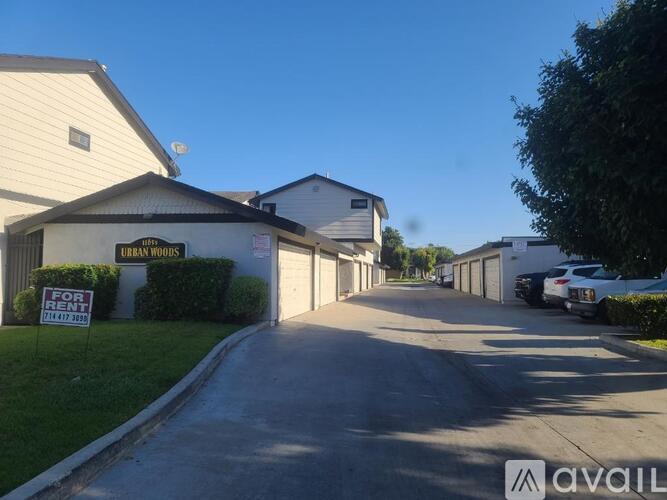 A street view of a residential area with houses and a for sale sign.
