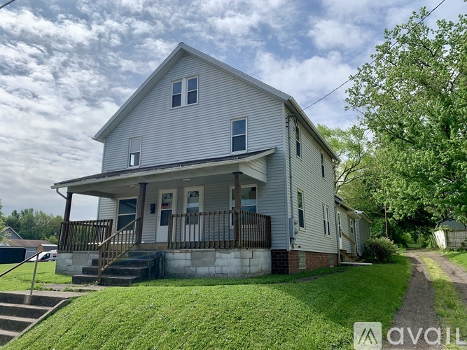 A house with a porch and a tree in front.