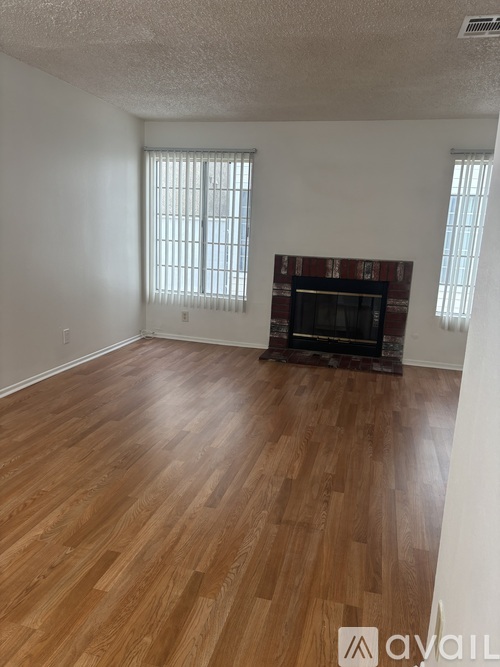 A room with wooden flooring and a fireplace.