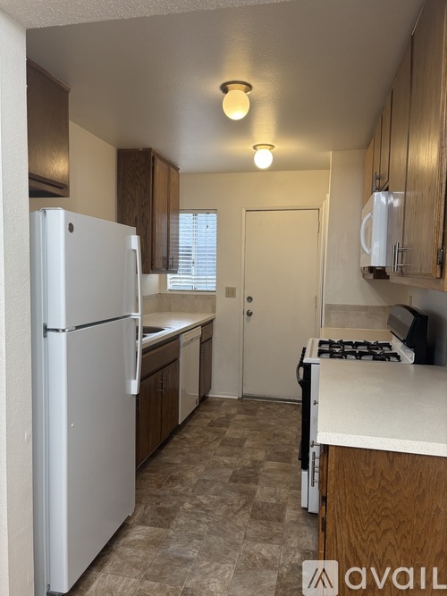 A kitchen with a white refrigerator and wooden cabinets.