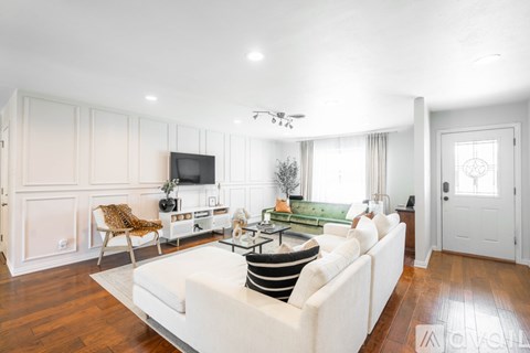 A living room with a white couch and a television on the wall.