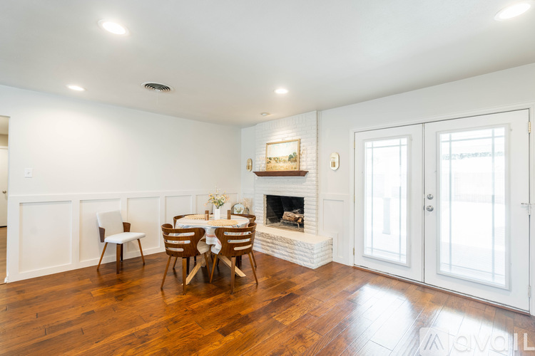A dining room with a fireplace and wooden floors.