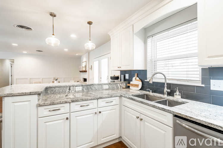 A kitchen with white cabinets and a marble countertop.
