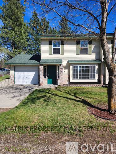 A house with a green lawn and a tree in front of it.