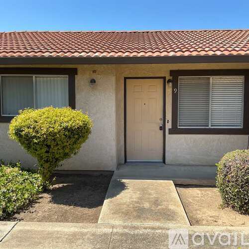 A house with a white door and a small bush in front.