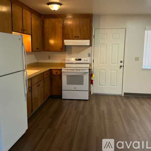 A kitchen with white appliances and wooden cabinets.