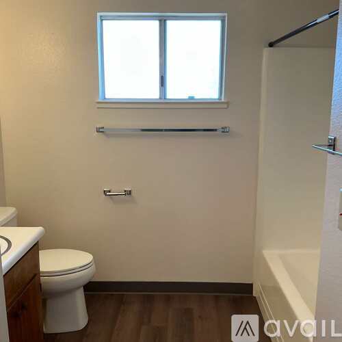 A bathroom with a toilet, a window, and a bathtub.