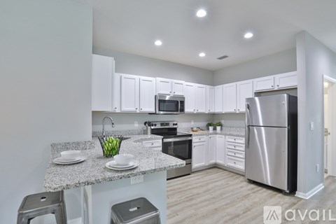 A kitchen with white cabinets and a stainless steel refrigerator.