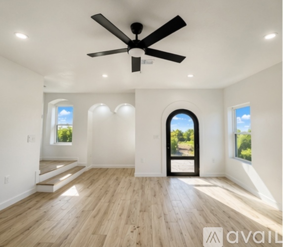 A spacious room with a ceiling fan and wooden flooring.