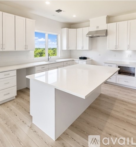 A white kitchen with wooden floors and a large island.