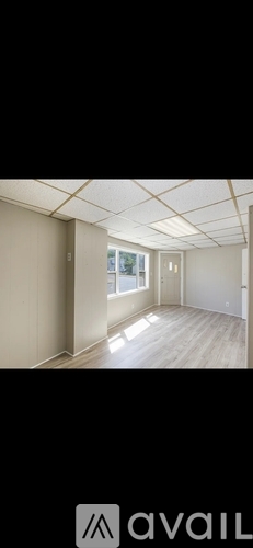 A room with a window and a wooden floor.