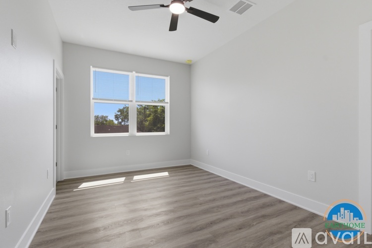 A room with a ceiling fan and a window with a view of trees.