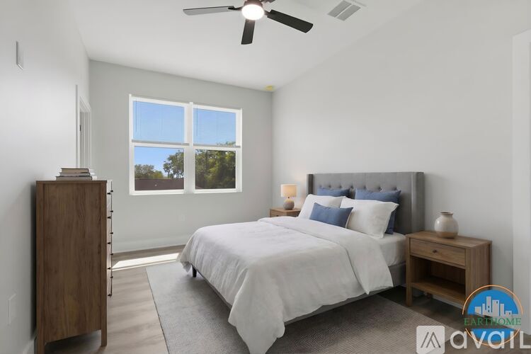 A bedroom with a large bed, a ceiling fan, and a window with a view of trees.