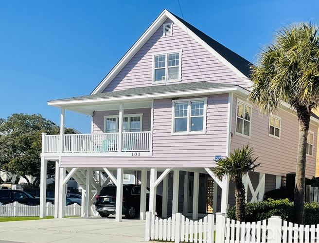 A pink house with a white picket fence in front.