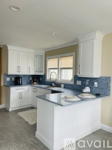 A kitchen with white cabinets and a marble countertop.