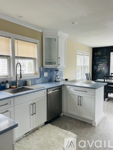 A kitchen with white cabinets and a blackboard on the wall.