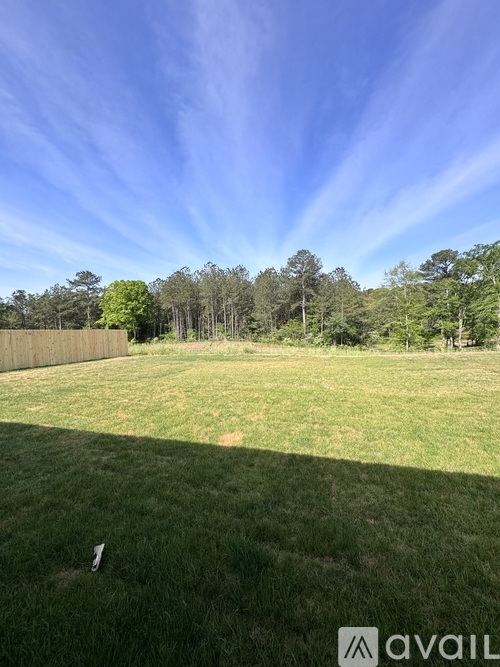 A backyard with a well-maintained lawn and trees in the background.