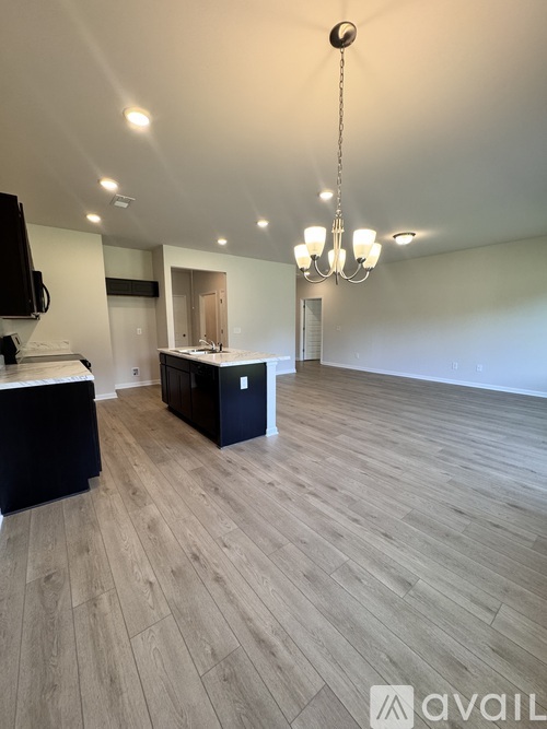 A spacious room with wooden flooring and a chandelier.
