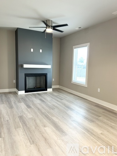 A spacious living room with a fireplace and wood flooring.