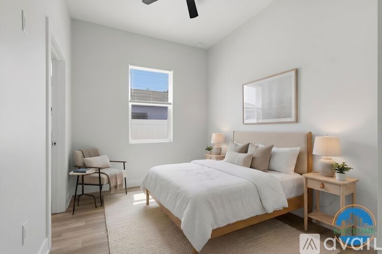 A bedroom with a large bed, a chair, and a window.