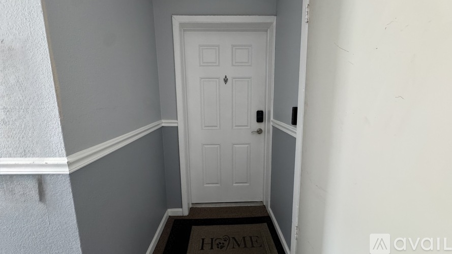 A white door is in a hallway with a brown doormat.