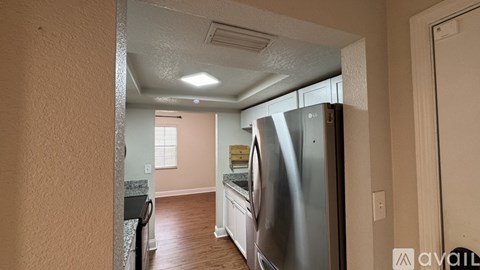 A kitchen with a stainless steel refrigerator and wooden flooring.