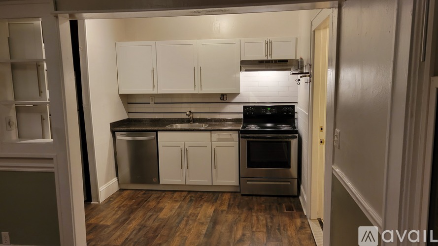 A kitchen with white cabinets and a wooden floor.