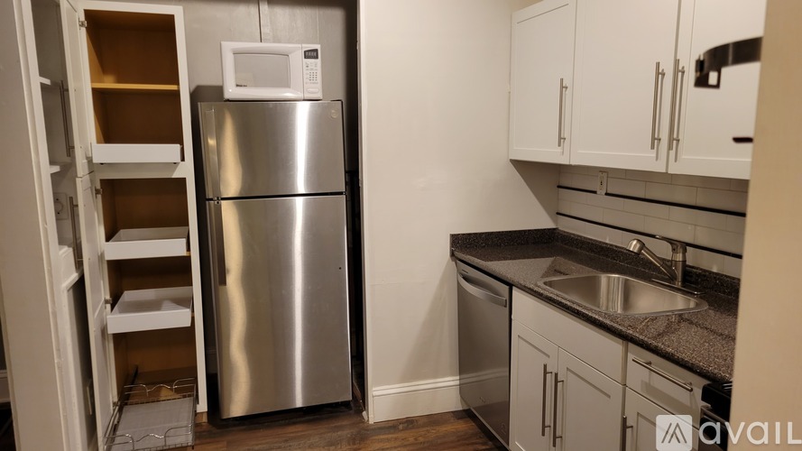 A kitchen with a stainless steel refrigerator and white cabinets.
