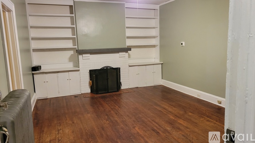 A room with wooden floors and a staircase with white railings.