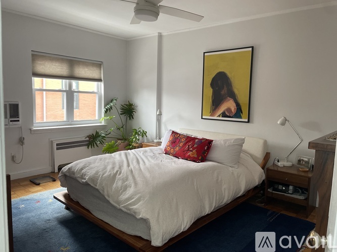 A bedroom with a bed, a ceiling fan, and a painting on the wall.