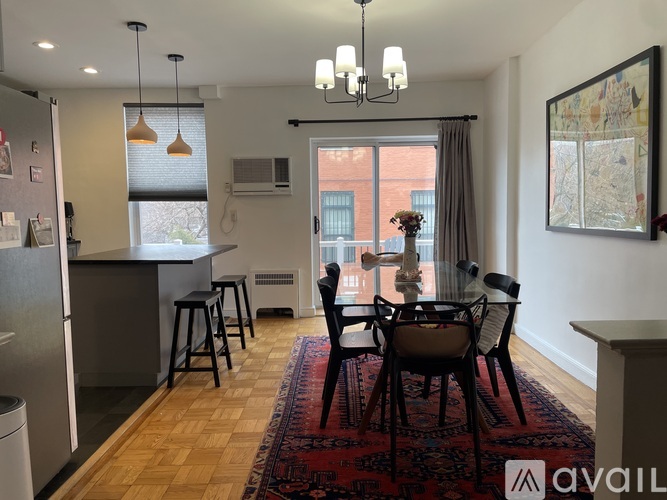 A kitchen with a refrigerator, bar stools, and a dining table with chairs.