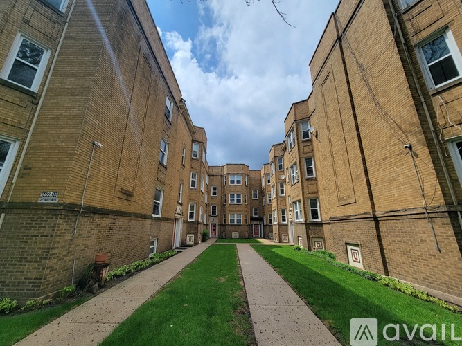 A long pathway leads to a building entrance between two brick buildings.