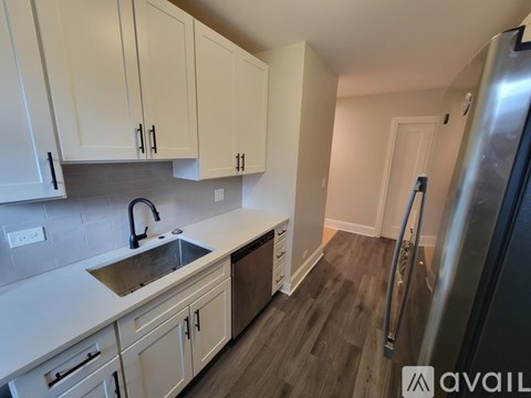 A kitchen with white cabinets and a stainless steel refrigerator.