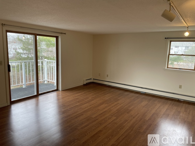 A room with wooden flooring and a sliding glass door leading to a balcony.