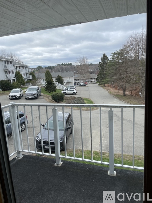 A view from a balcony overlooking a parking lot with cars and houses in the distance.