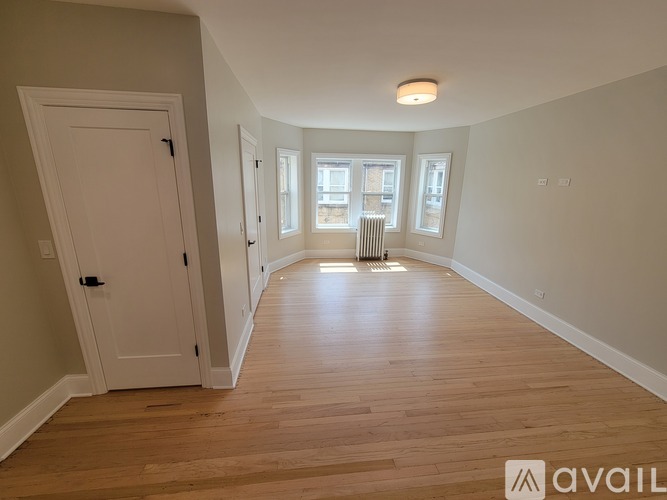 A spacious room with wooden floors and a large window.