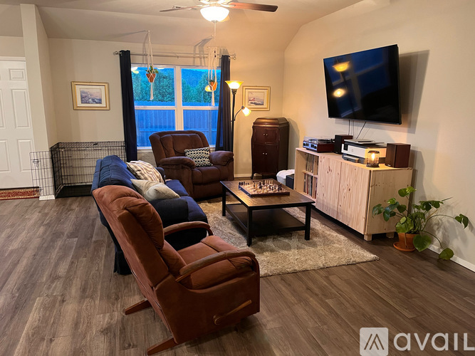 A living room with a brown couch and a television on the wall.