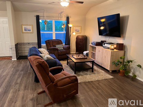 A living room with a brown couch and a television on the wall.