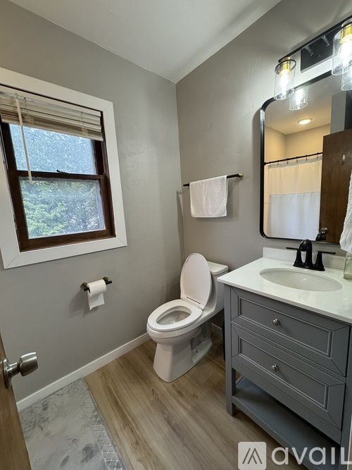 A bathroom with a toilet, sink, and mirror.