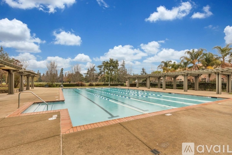 A large outdoor swimming pool surrounded by trees and a cloudy sky.