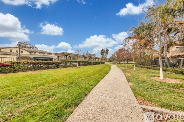 A concrete walkway leads through a grassy area with a building in the background.