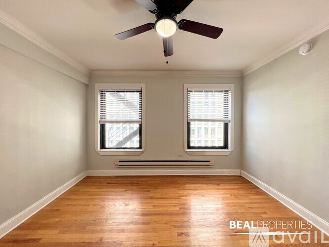 A room with a ceiling fan and two windows.