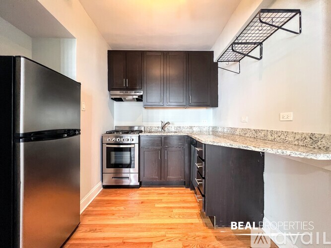 A kitchen with a black fridge and stove top oven.
