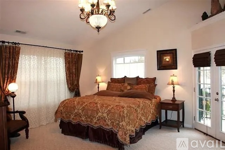 A bedroom with a large bed and a chandelier.