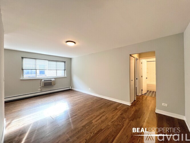 A spacious room with wooden floors and a large window.